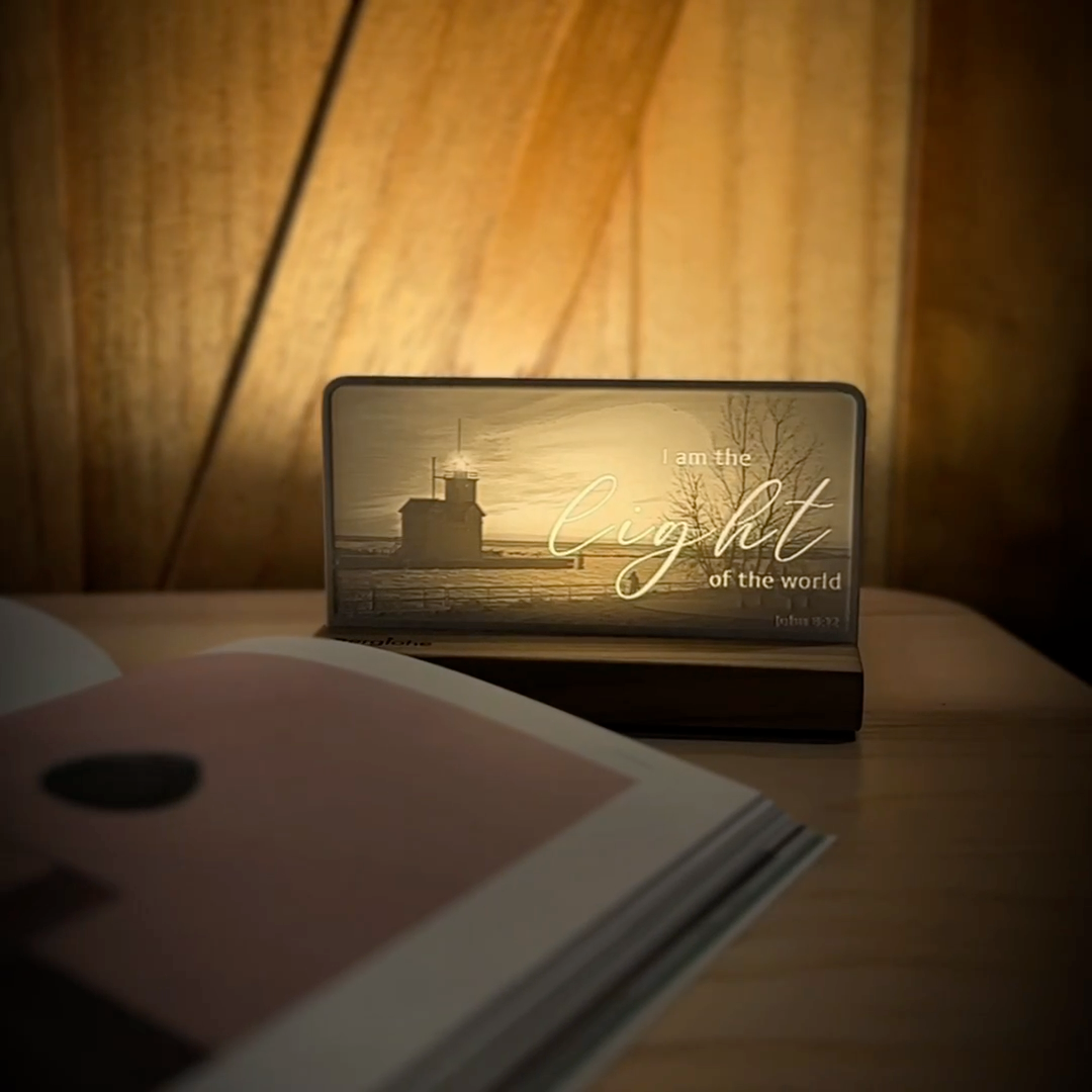 StoryLine-Mini lithophane photo display lit with Warm LED featuring a lighthouse beach scene and encouraging Bible verse rotating on a small table