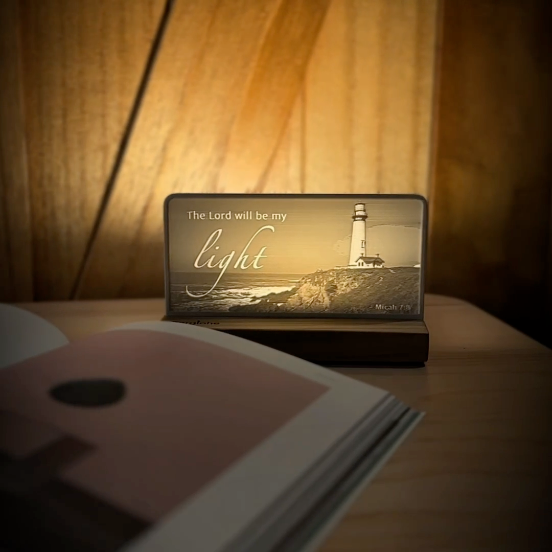 StoryLine-Mini lithophane photo display lit with Warm LED featuring a lighthouse beach scene and encouraging Bible verse rotating on a small table