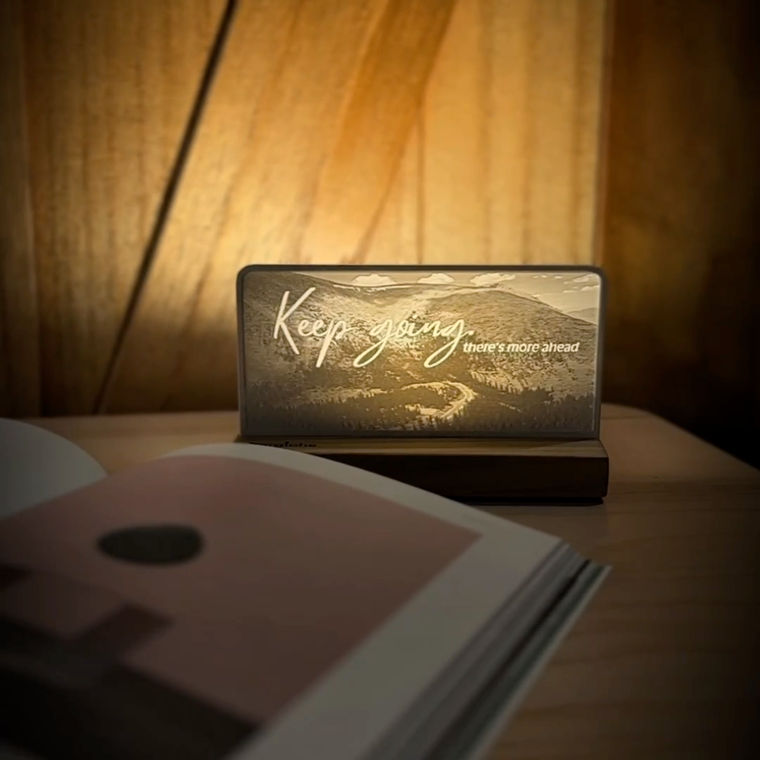 StoryLine-Mini lithophane photo display lit with Warm LED featuring a mountain scene and encouraging saying rotating on a small table