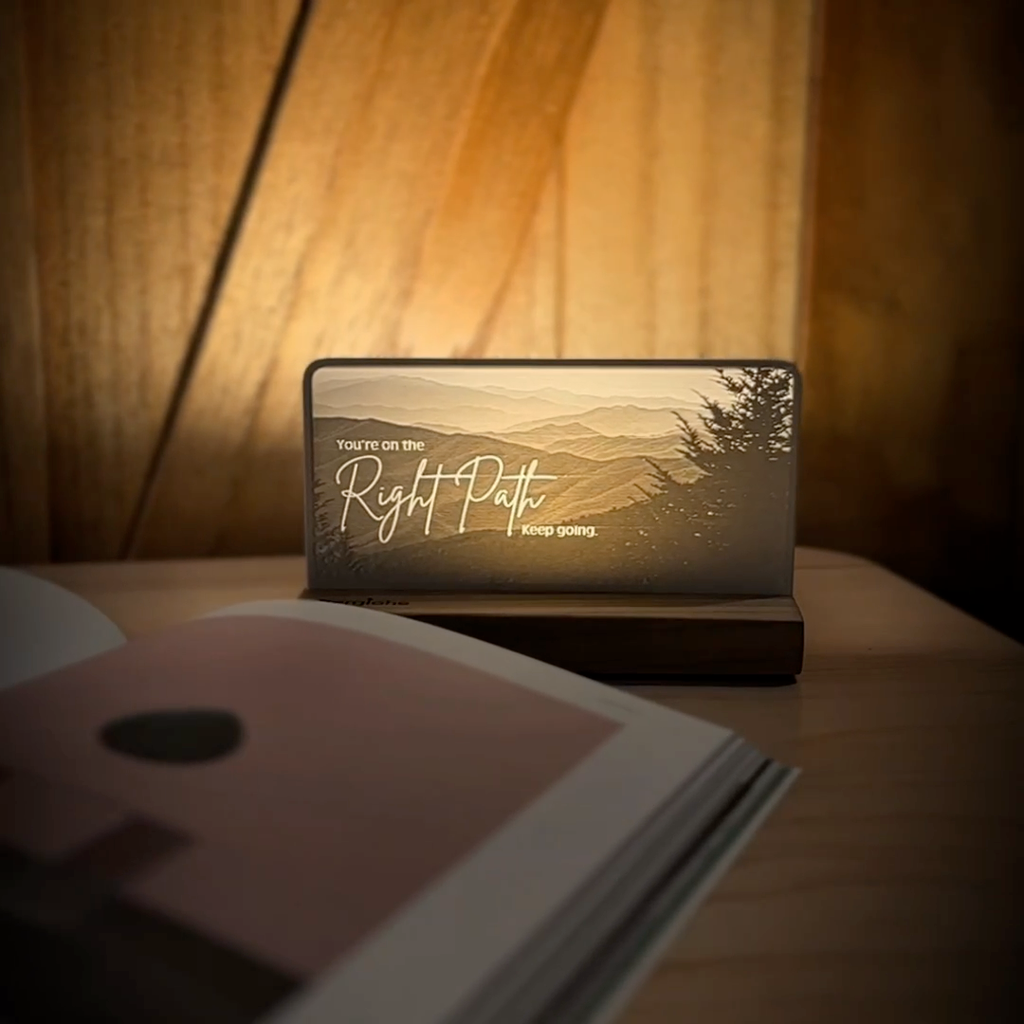 StoryLine-Mini lithophane photo display lit with Warm LED featuring a mountain scene and encouraging saying rotating on a small table