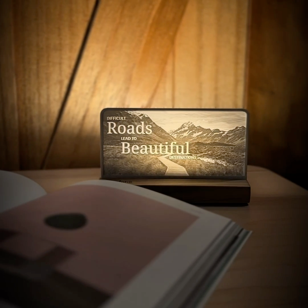 StoryLine-Mini lithophane photo display lit with Warm LED featuring a mountain scene and encouraging saying rotating on a small table