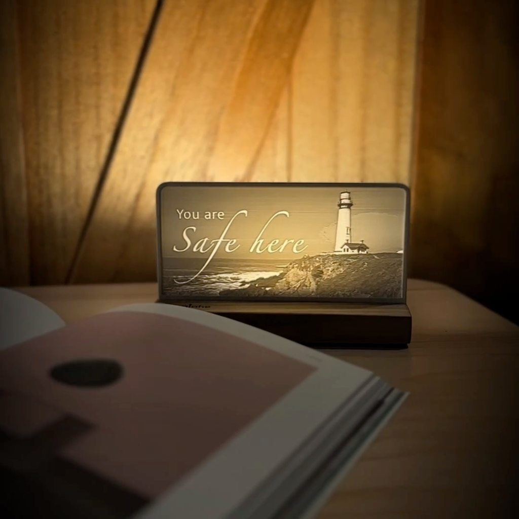 StoryLine-Mini lithophane photo display lit with Warm LED featuring a beach lighthouse scene and encouraging saying rotating on a small table