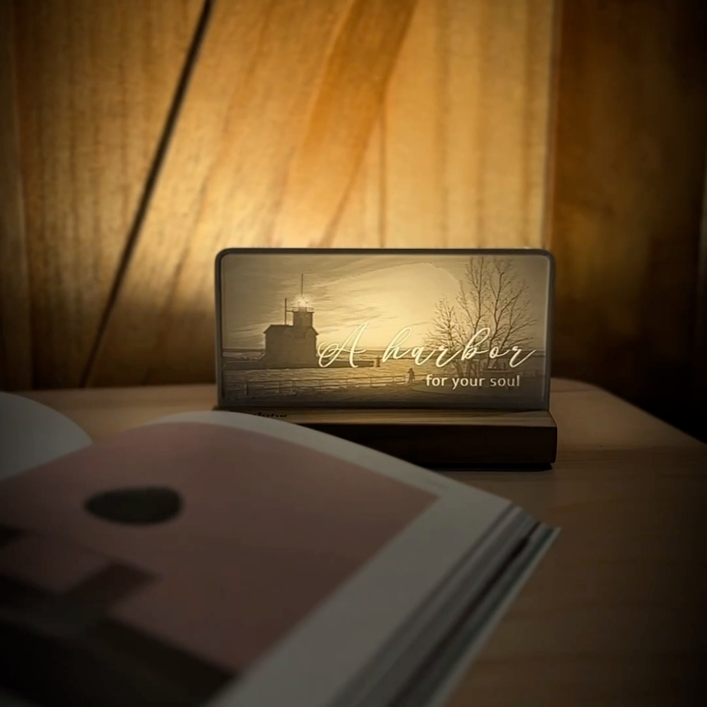 StoryLine-Mini lithophane photo display lit with Warm LED featuring a beach lighthouse scene and encouraging saying rotating on a small table