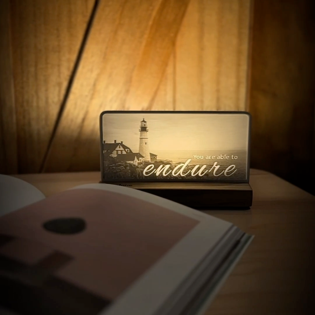 StoryLine-Mini lithophane photo display lit with Warm LED featuring a beach lighthouse scene and encouraging saying rotating on a small table