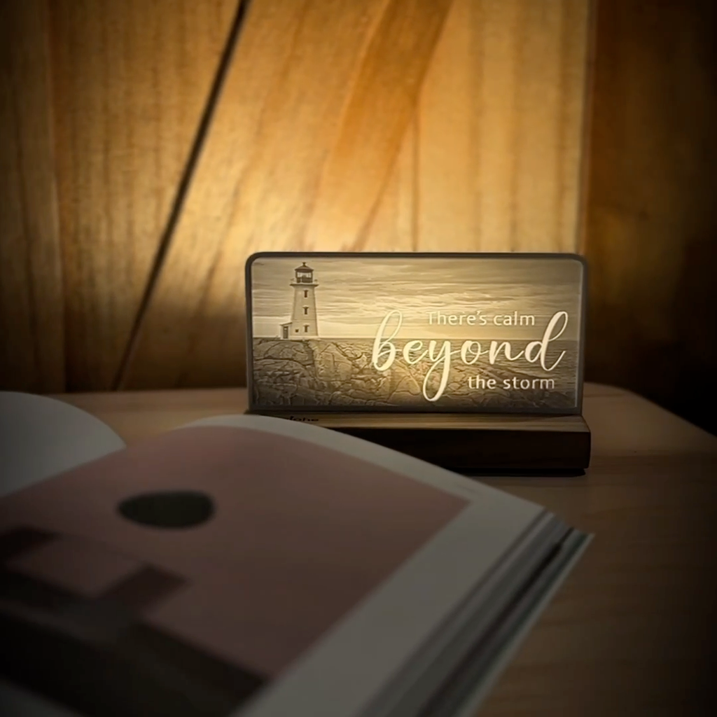 StoryLine-Mini lithophane photo display lit with Warm LED featuring a beach lighthouse scene and encouraging saying rotating on a small table
