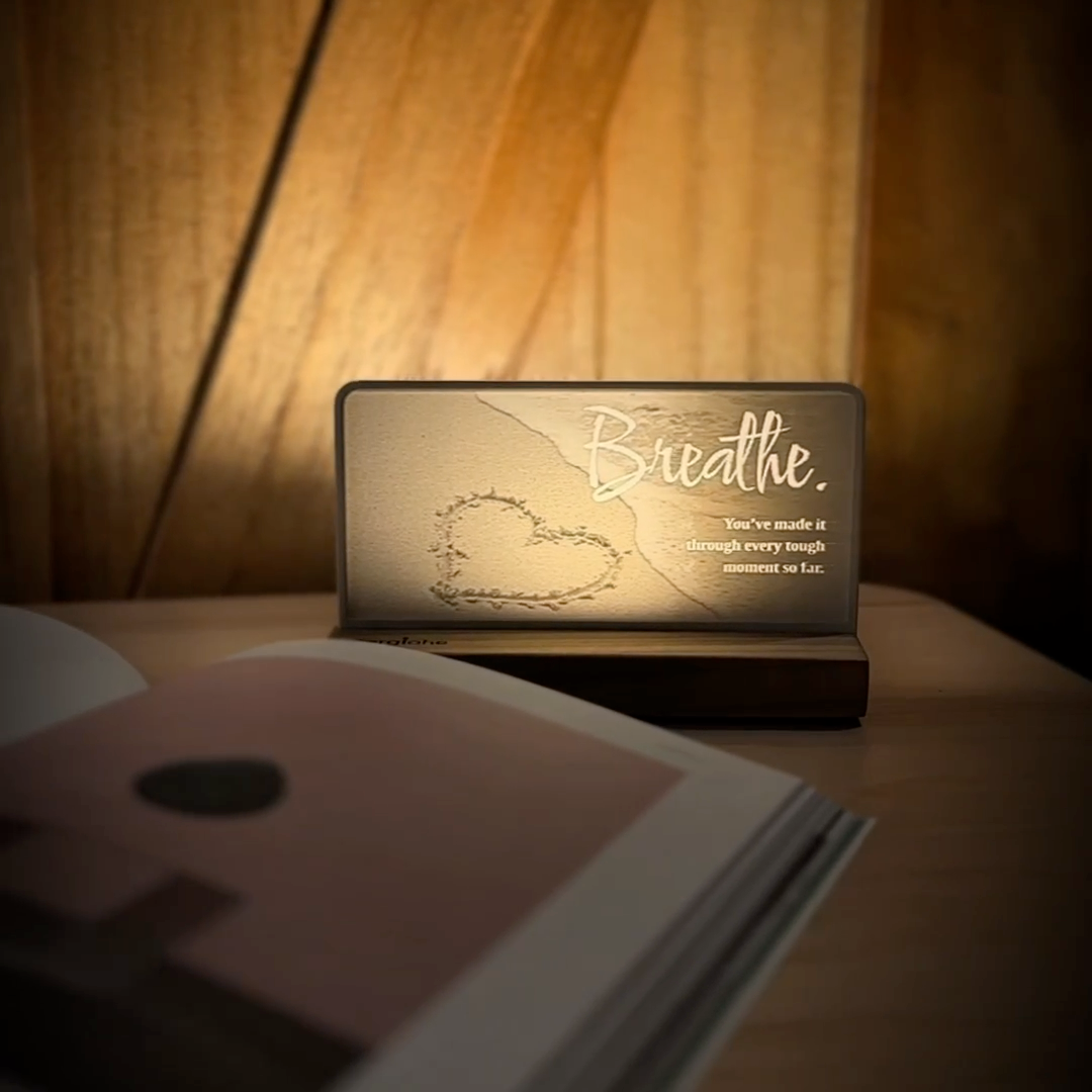 StoryLine-Mini lithophane photo display lit with Warm LED featuring a beach lighthouse scene and encouraging saying rotating on a small table