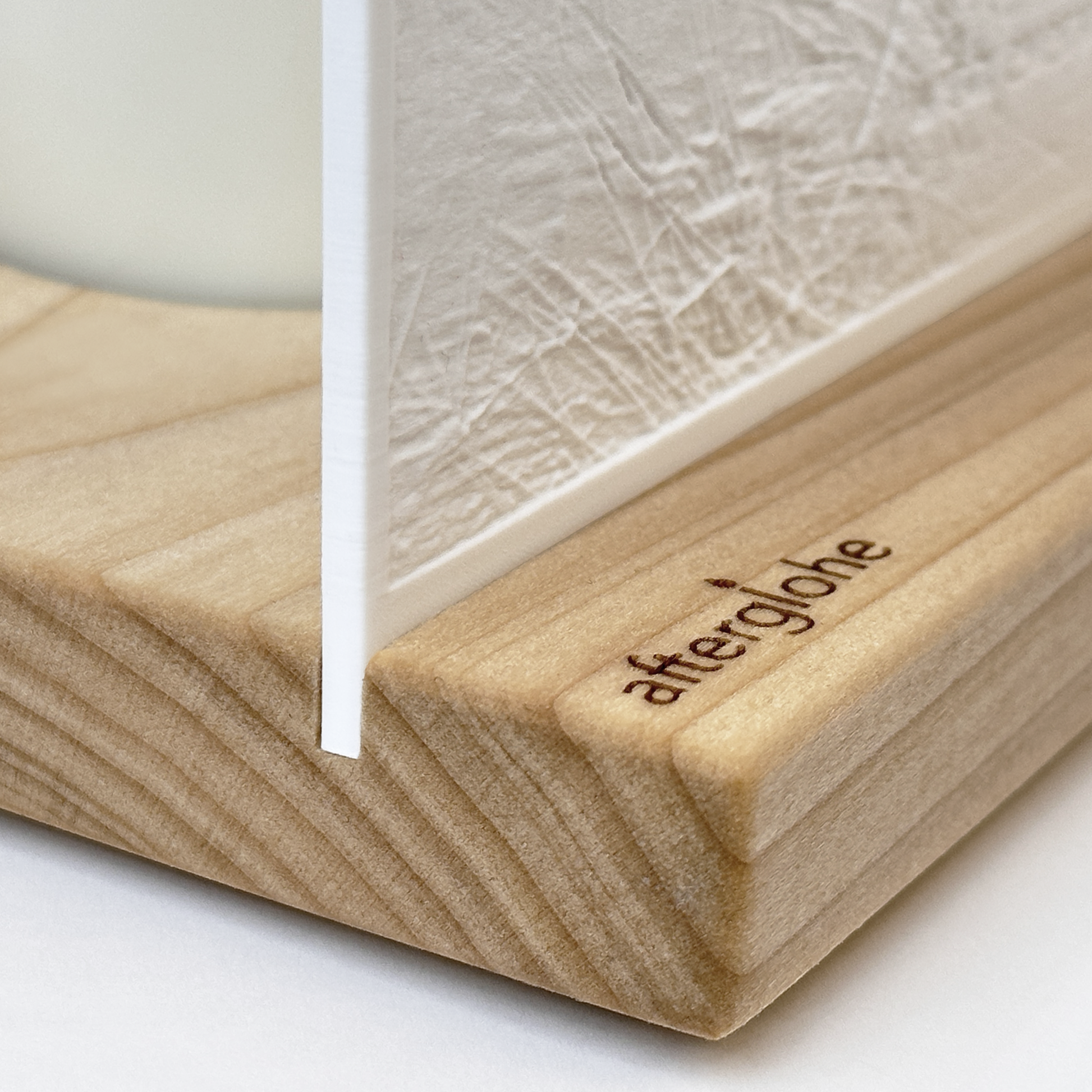 Close-up detail of afterglohe StoryLine-Mini product showing hardwood base and logo engraving, white lithophane photo canvas, and scented candle in background